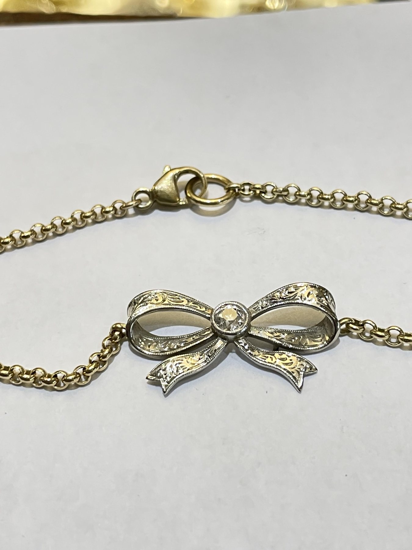 Fine hand-cut scroll engraving across an antique bow brooch