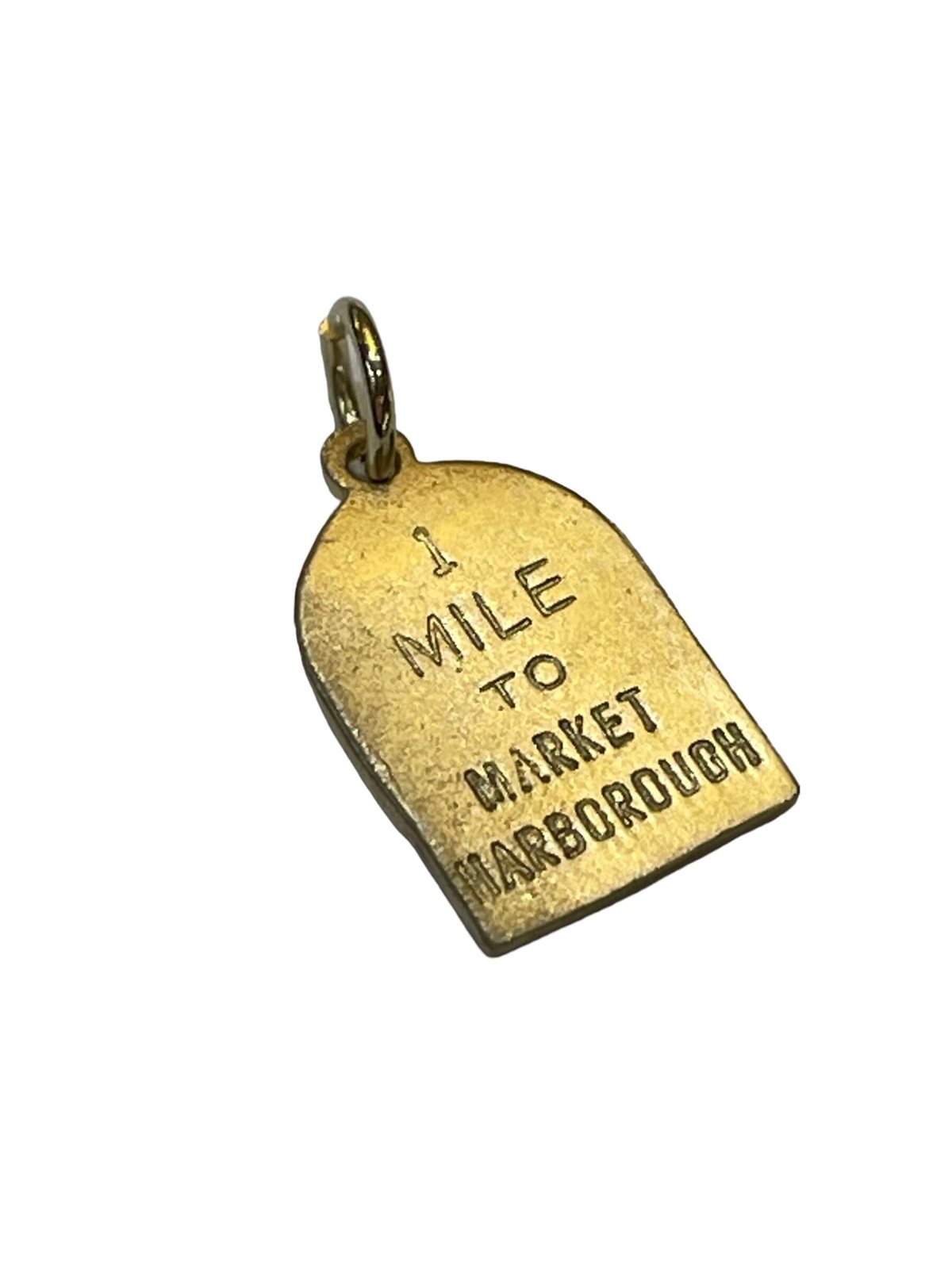 A gold milestone charm hand engraved one mile to Market Harborough